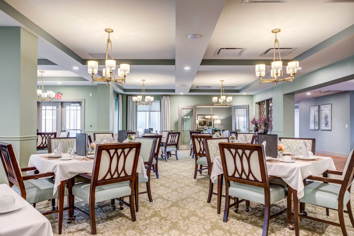 An elegant dining room with neatly arranged tables and chandeliers.