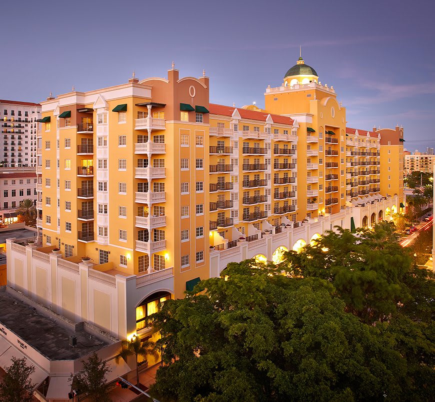 A brightly lit hotel building in an urban setting during the evening.