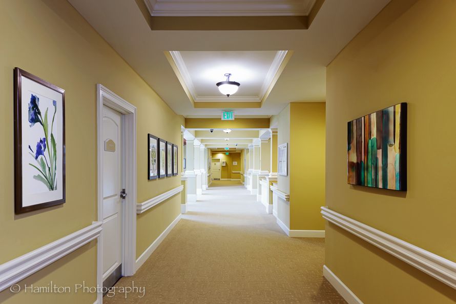 A well-lit hallway with artwork and doors on either side.