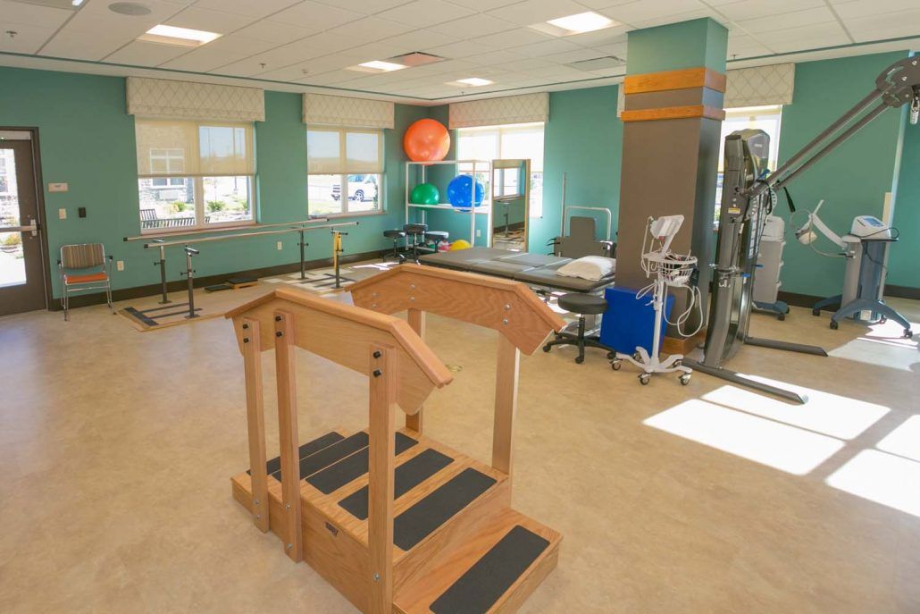 A spacious physical therapy room equipped with exercise equipment and wooden steps for rehabilitation exercises.