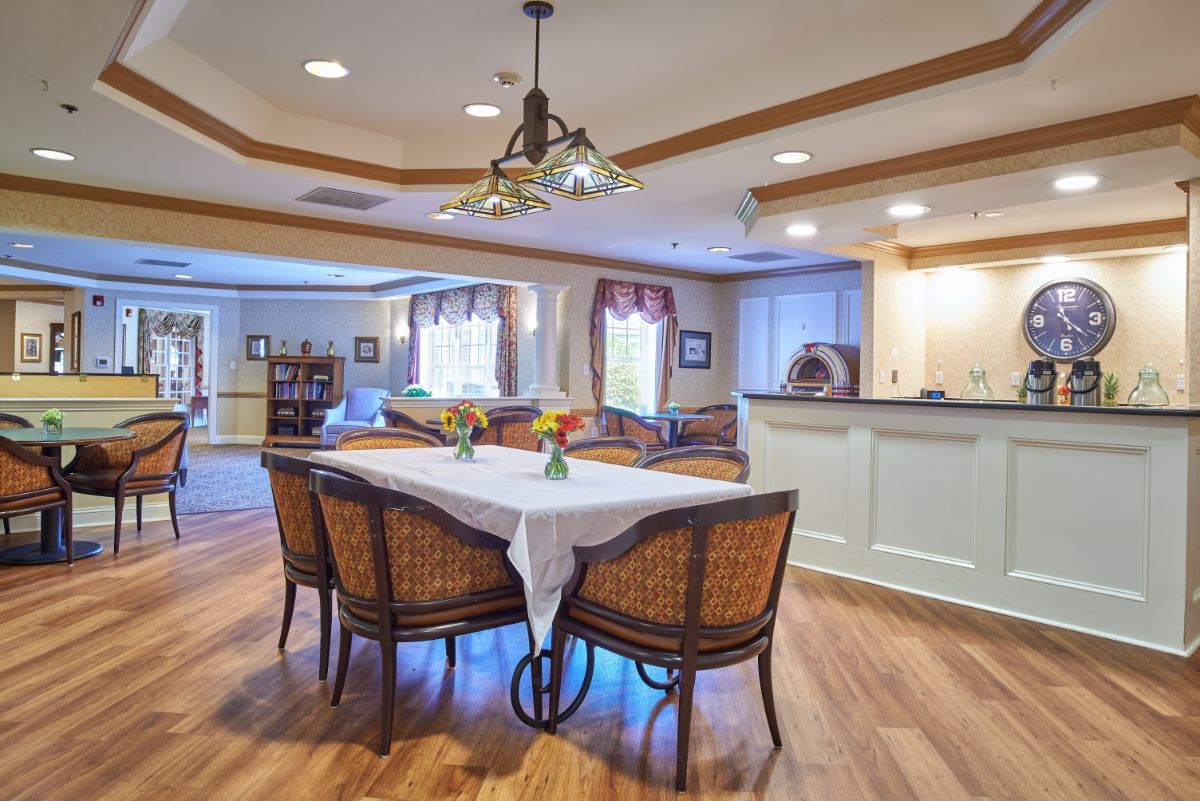 A cozy dining room with a table set for four, featuring elegant lighting and wooden flooring.