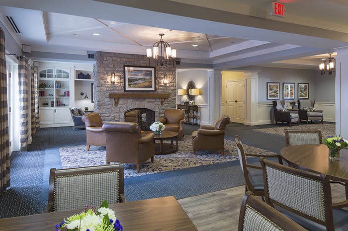 A cozy living room with comfortable seating surrounding a brick fireplace, featuring elegant interior design and warm lighting.