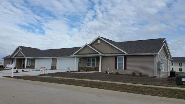 A suburban house with a driveway and front yard under a cloudy sky.