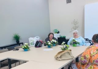 A group of people sitting around a table with floral arrangements.