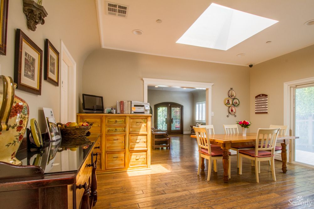 A cozy dining room featuring wooden furniture and a skylight, illuminating the hardwood floors.