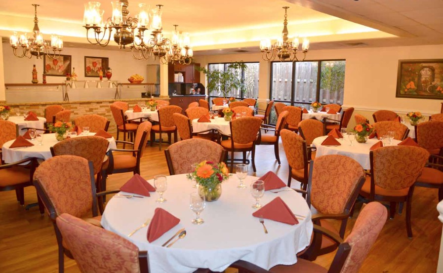 An elegant dining area with neatly arranged tables and chairs, adorned with chandeliers.