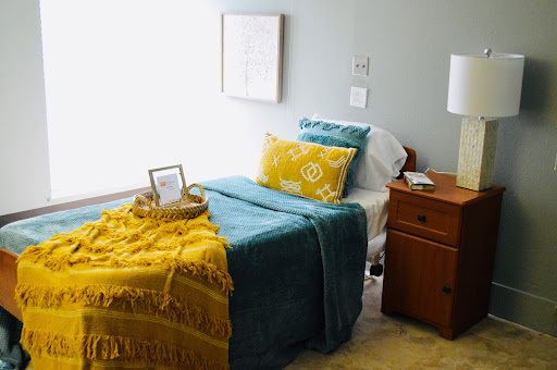 A cozy and colorful bedroom setup featuring a neatly made bed with decorative pillows and a warm throw.