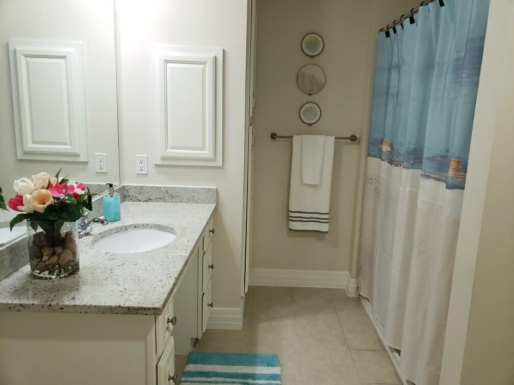A neat and organized bathroom featuring a marble countertop, mirror, and blue-themed decor.