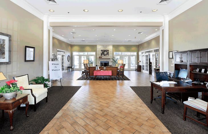 A modern lobby with a central reception desk, bright lighting, and elegant furnishing.