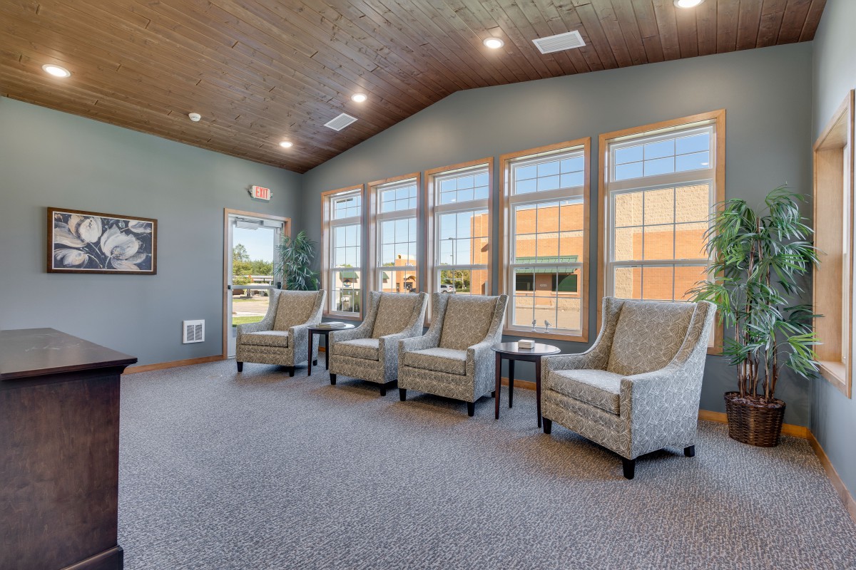 A modern waiting room with large windows and comfortable seating.