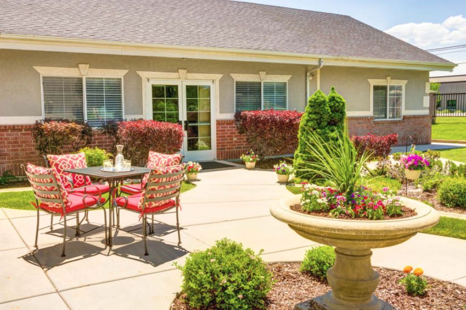 A sunny patio area with outdoor seating, surrounded by vibrant garden landscaping.