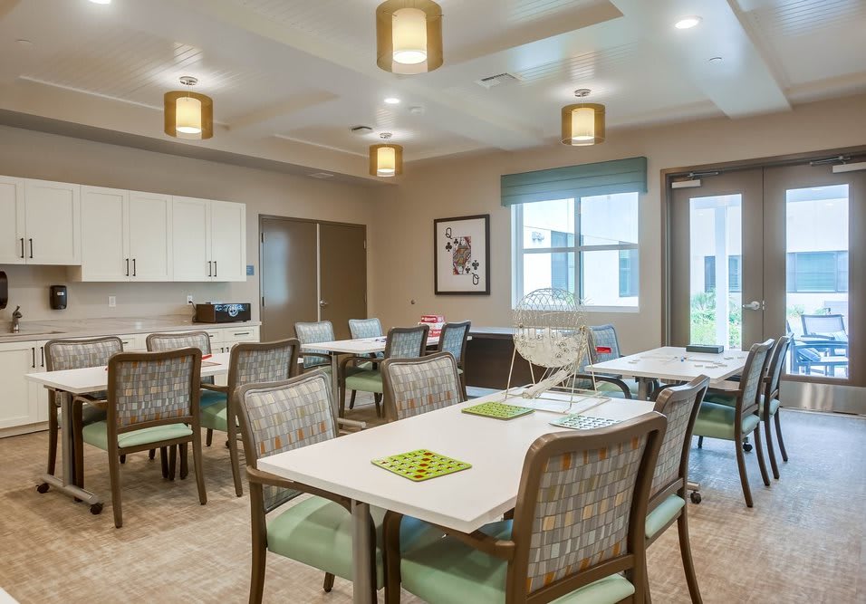 A modern dining room interior with tables and chairs arranged neatly under warm lighting.