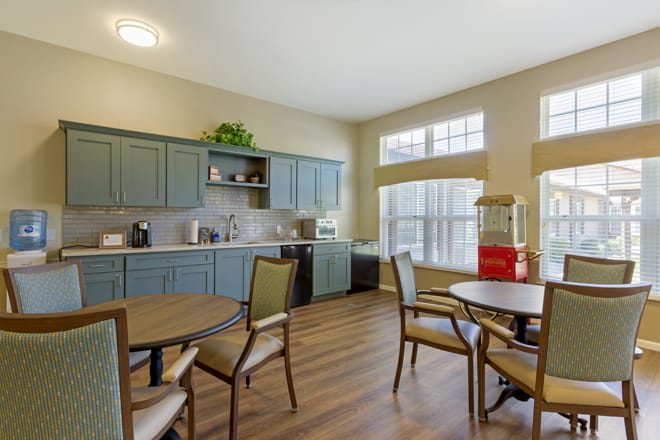A cozy kitchen and dining area with tables, chairs, and large windows.