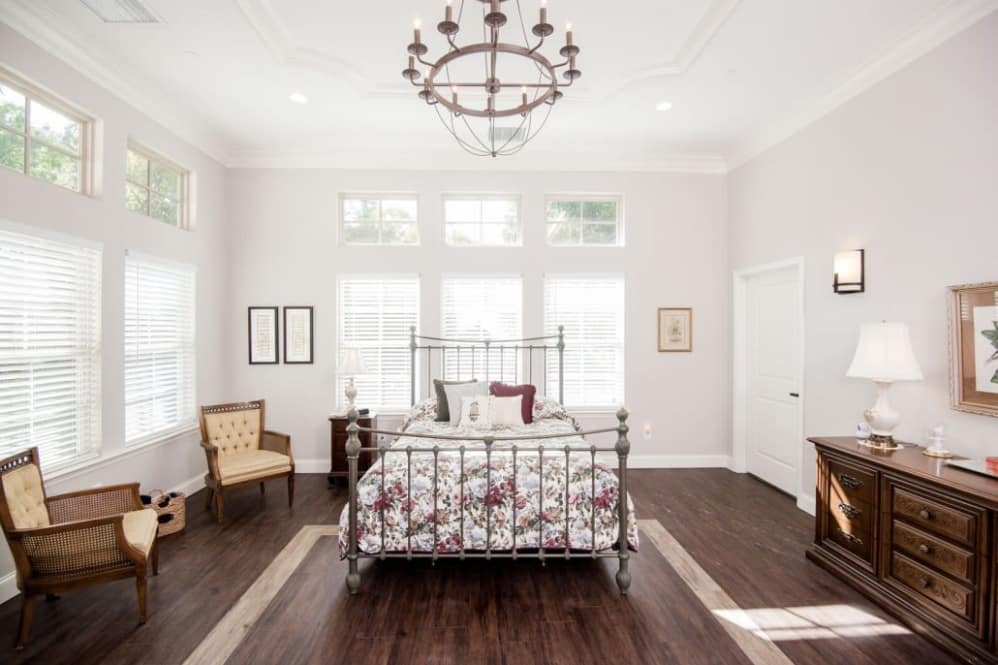 Cozy vintage-style bedroom with a metal bed frame, elegant chandelier, and wooden flooring.