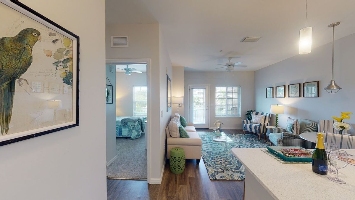 A modern apartment interior featuring a cozy living room with stylish furniture and decor, leading into a bedroom.