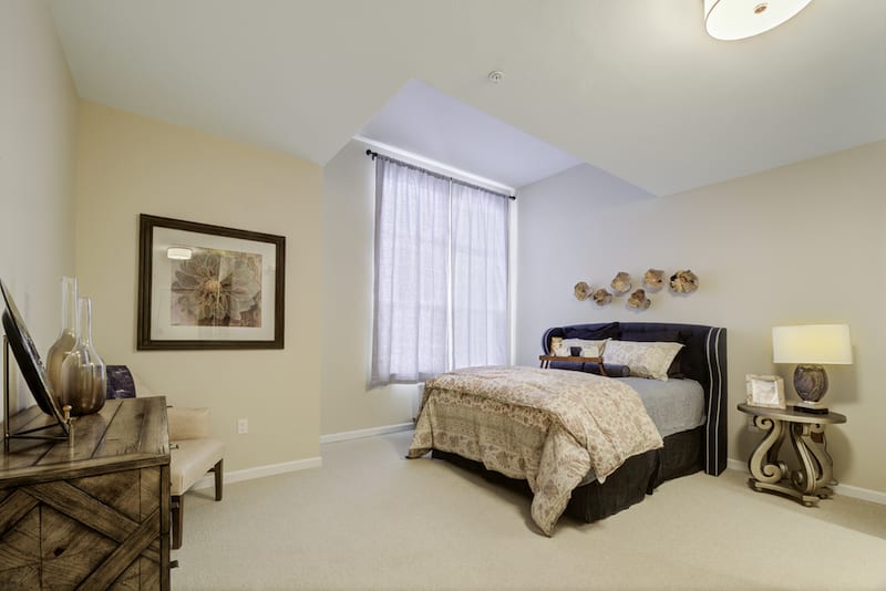 A neatly arranged bedroom with a large window and decorative art.