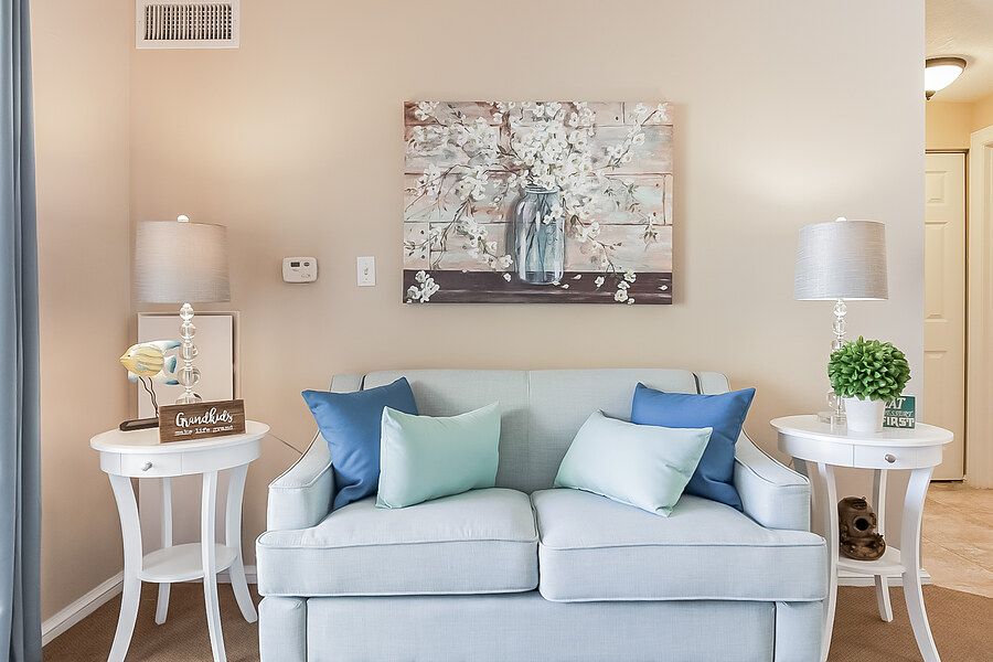 A cozy living room with a pastel sofa, decorative pillows, and artwork on the wall.