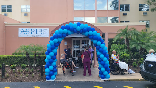 A colorful blue balloon arch welcoming visitors to a facility entrance, with people gathered outside.