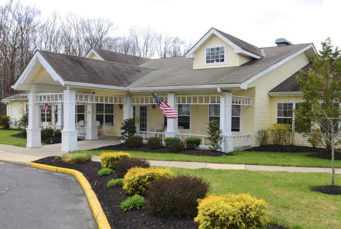 A charming yellow house with a well-maintained garden and an American flag displayed at the entrance.