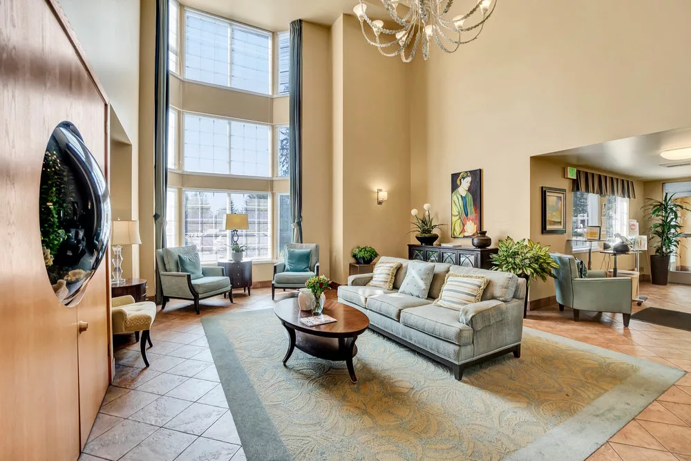 A spacious and well-lit living room with modern decor, featuring large windows, comfortable sofas, and elegant furnishings.