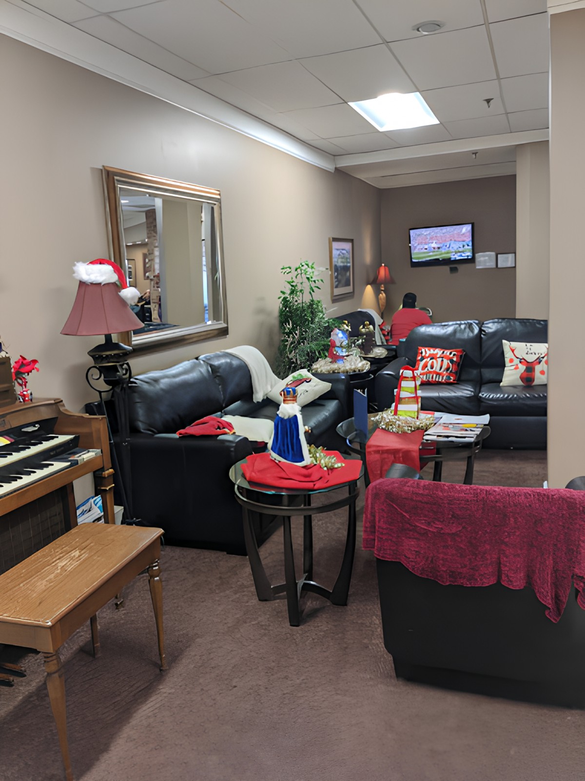 A cozy living room with a piano, sofas, and holiday decorations.