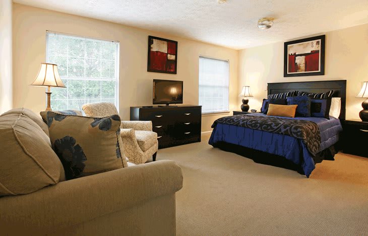 A cozy and well-furnished bedroom with a comfortable bed, dresser, and ample natural light.