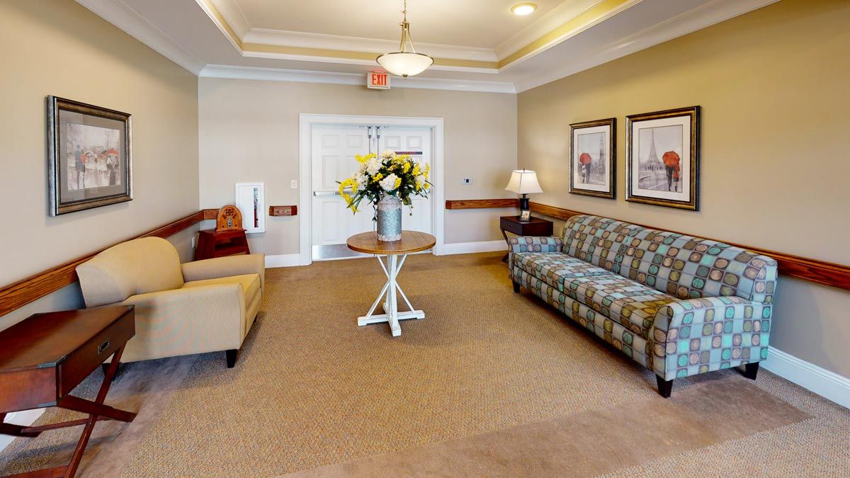 A cozy lobby area featuring sofas, a table with a floral arrangement, and wall art.