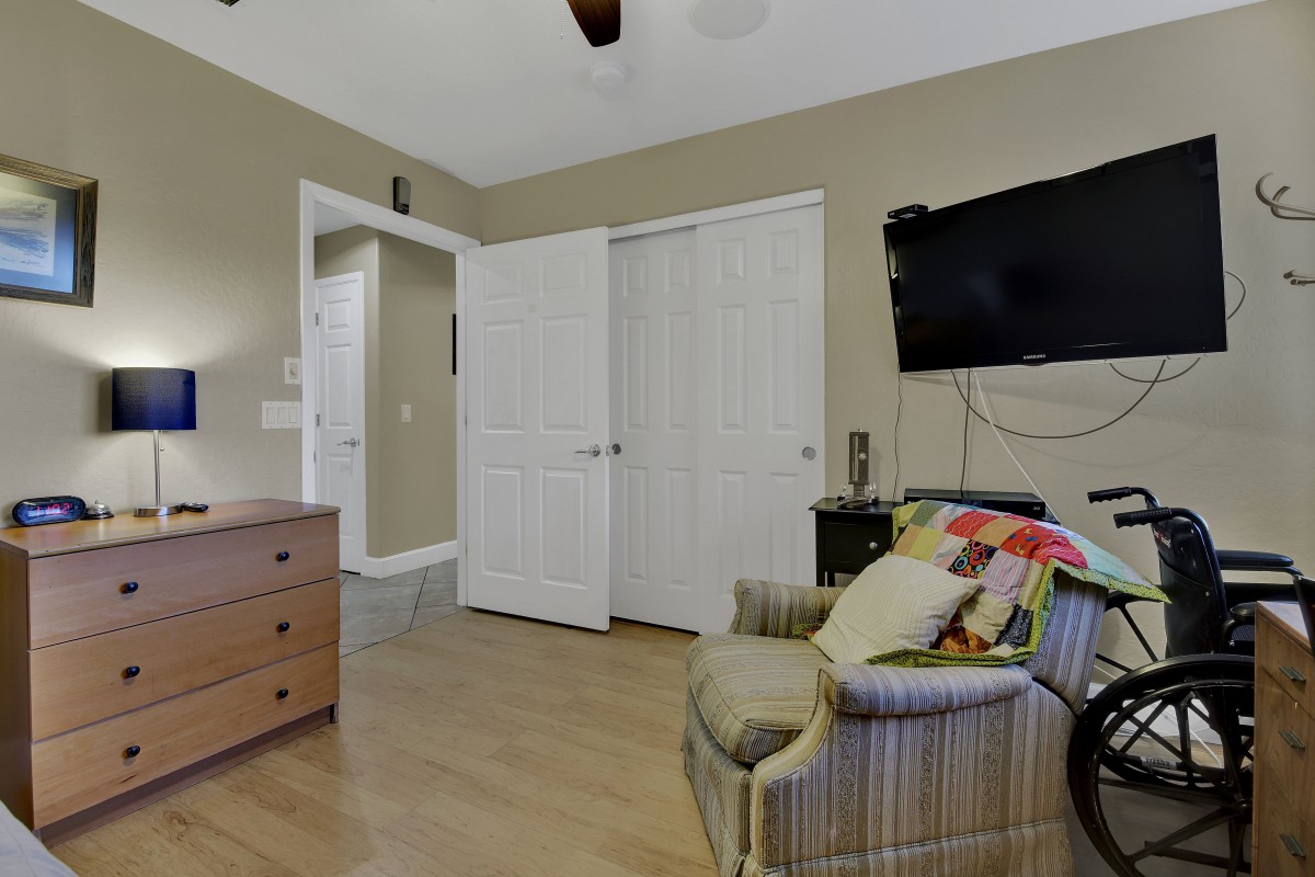 A cozy bedroom with a television, armchair, and open closet doors.