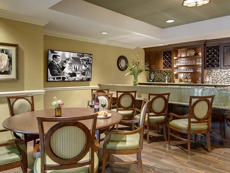A cozy restaurant dining area with elegant furniture, a bar, and a television displaying a black and white image.