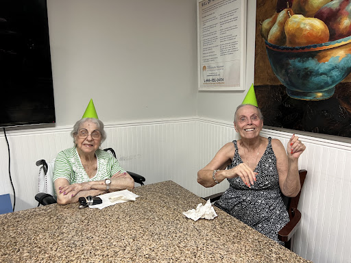 Two elderly women celebrating with party hats during a gathering.