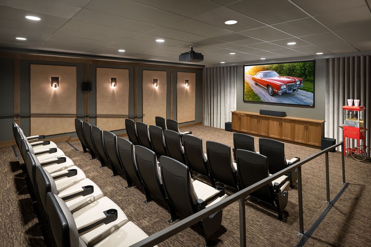 A home theater setup with tiered seating and a large projector screen displaying an image.