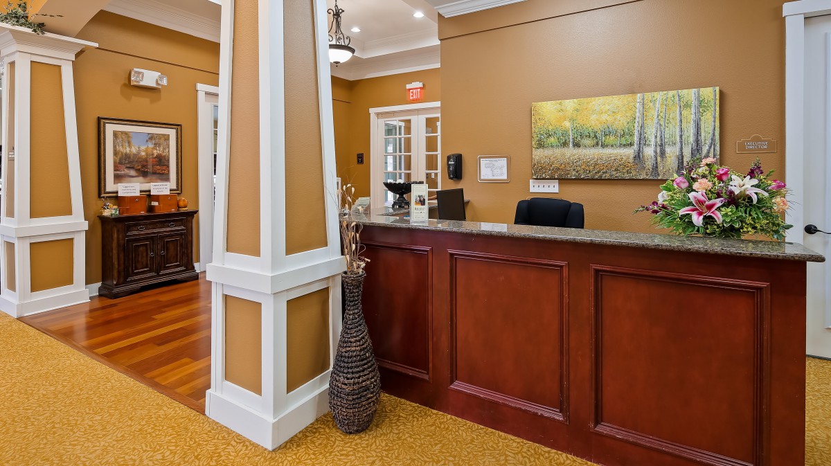 An elegant hotel reception area with a wooden desk and decorative elements.