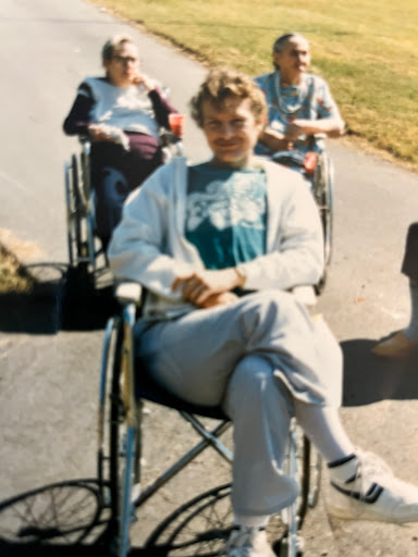 A cheerful group of individuals in wheelchairs enjoying a sunny day outdoors.