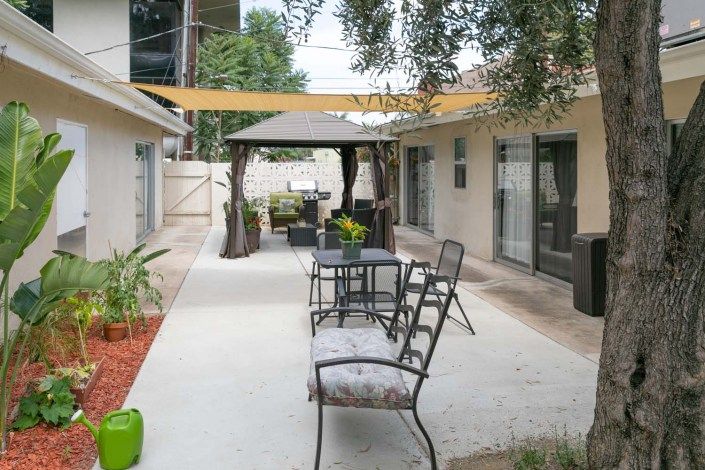 A cozy outdoor patio area with seating, a gazebo, and various plants.