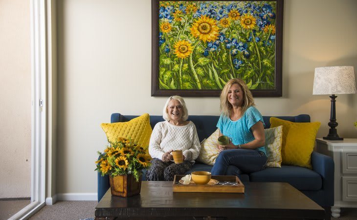 Two people relaxing in a cozy living room with sunflower-themed decor.