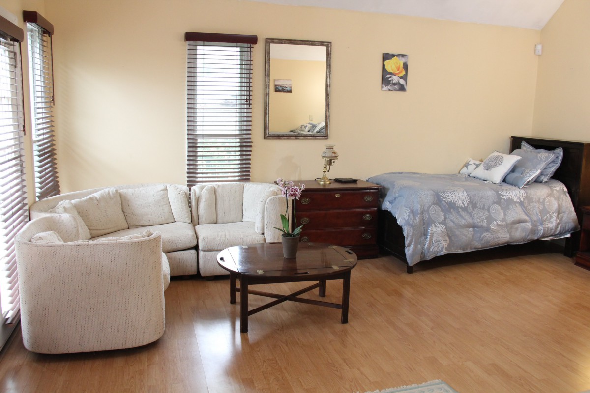 A cozy studio apartment with a combined bedroom and living area, featuring a sofa, coffee table, and bed.