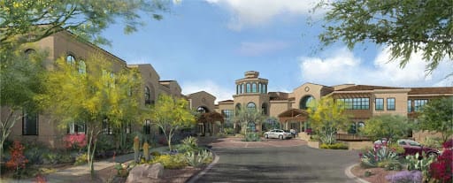 A scenic view of a resort building surrounded by desert landscape and greenery under a clear sky.