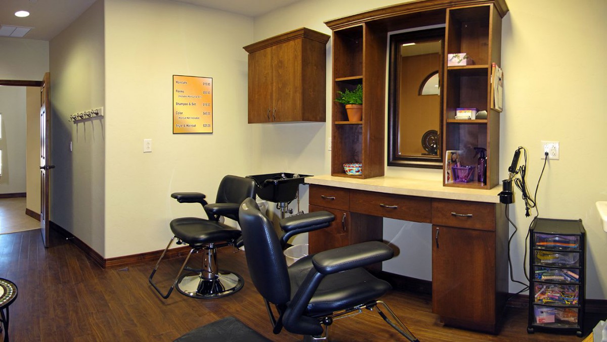 An interior view of a hair salon featuring styling chairs and a vanity with a mirror.