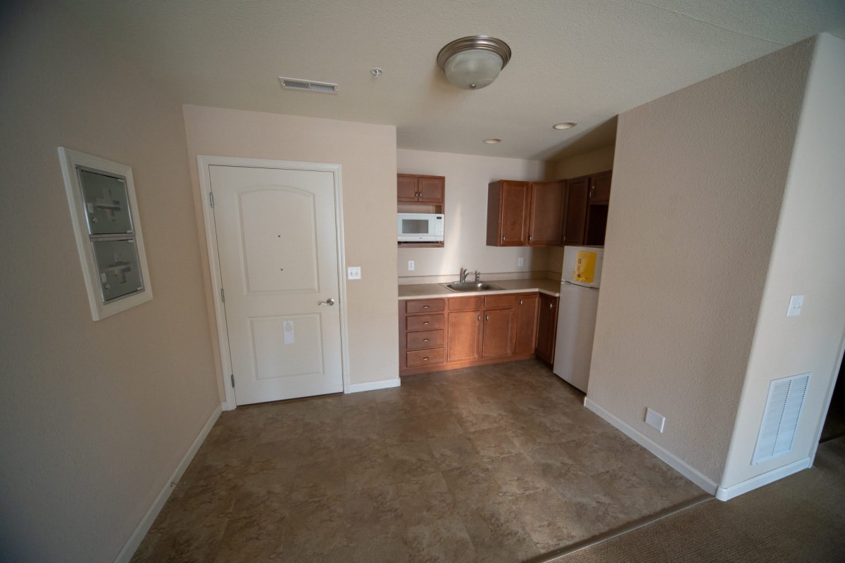 A compact kitchen area in an apartment with wooden cabinets and basic appliances.