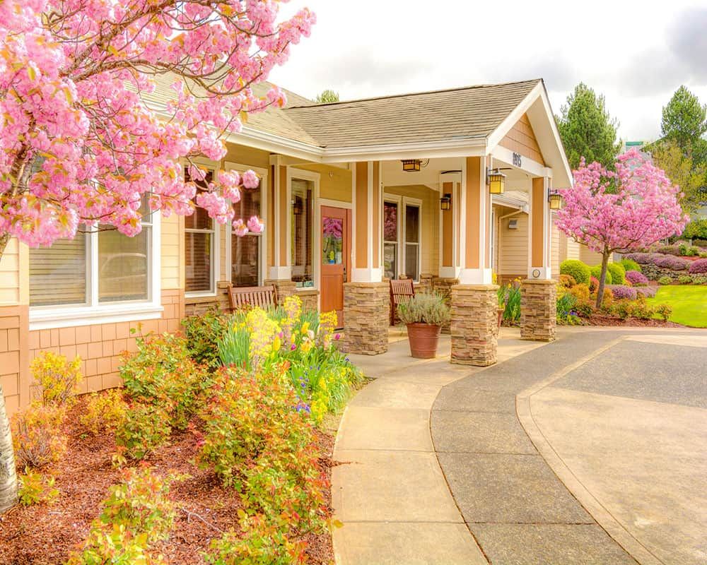 A charming house surrounded by blooming flowers and a well-maintained garden in springtime.