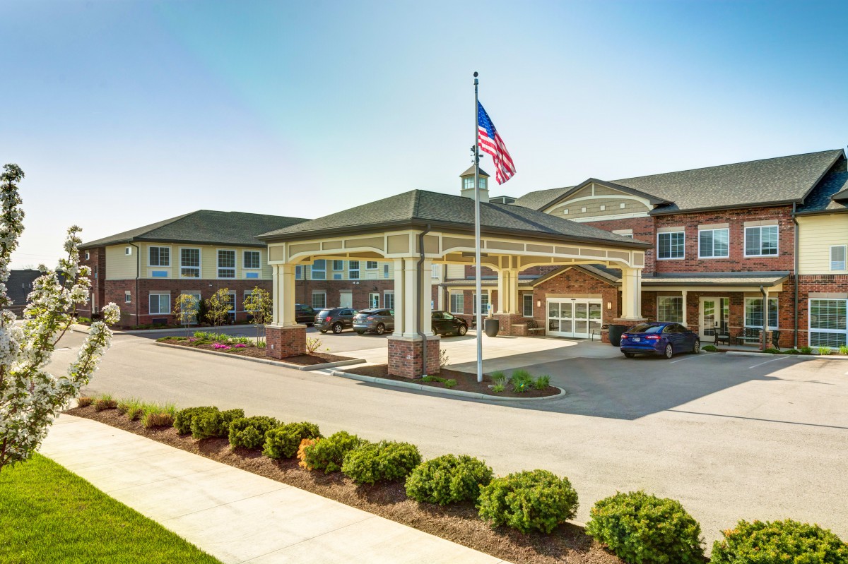 A well-maintained building with a grand entrance, featuring a flagpole and landscaped surroundings.