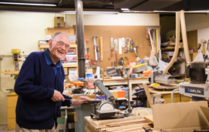 A person working in a woodworking workshop surrounded by tools and equipment.