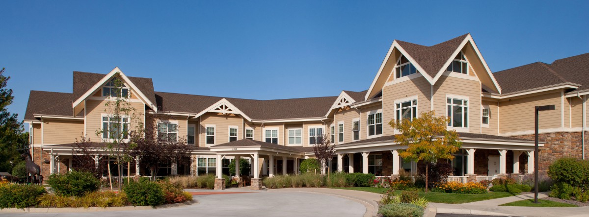 A large suburban house with a spacious porch under a clear blue sky.
