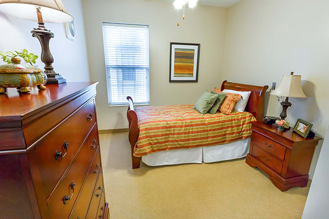 A cozy bedroom with warm tones, featuring a wooden bed and dresser.
