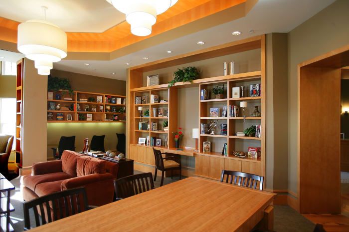 A cozy library space featuring wooden bookshelves, a reading area with comfortable seating, and modern interior design.
