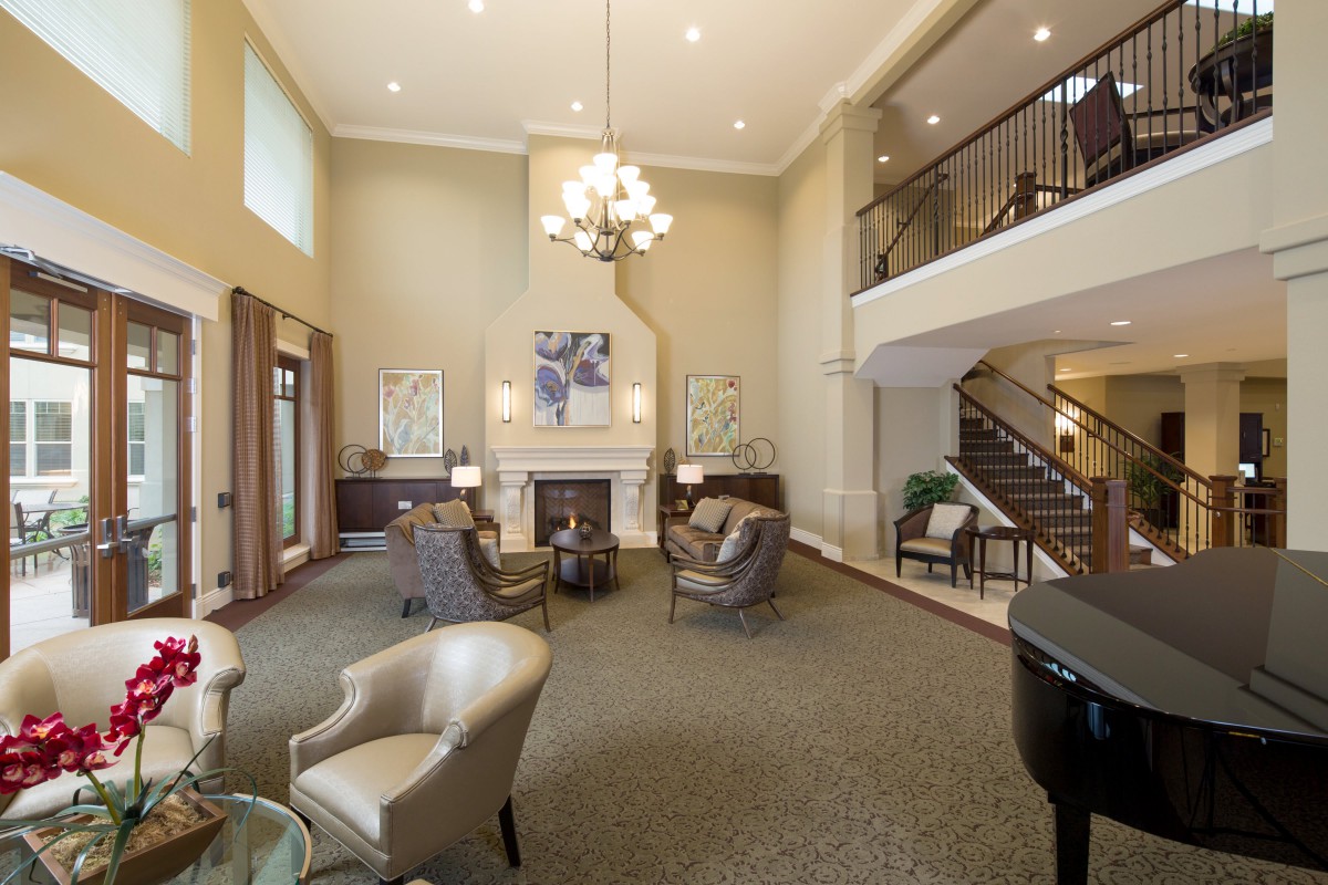 A spacious and elegant living room with a fireplace, chandelier, and comfortable seating area.