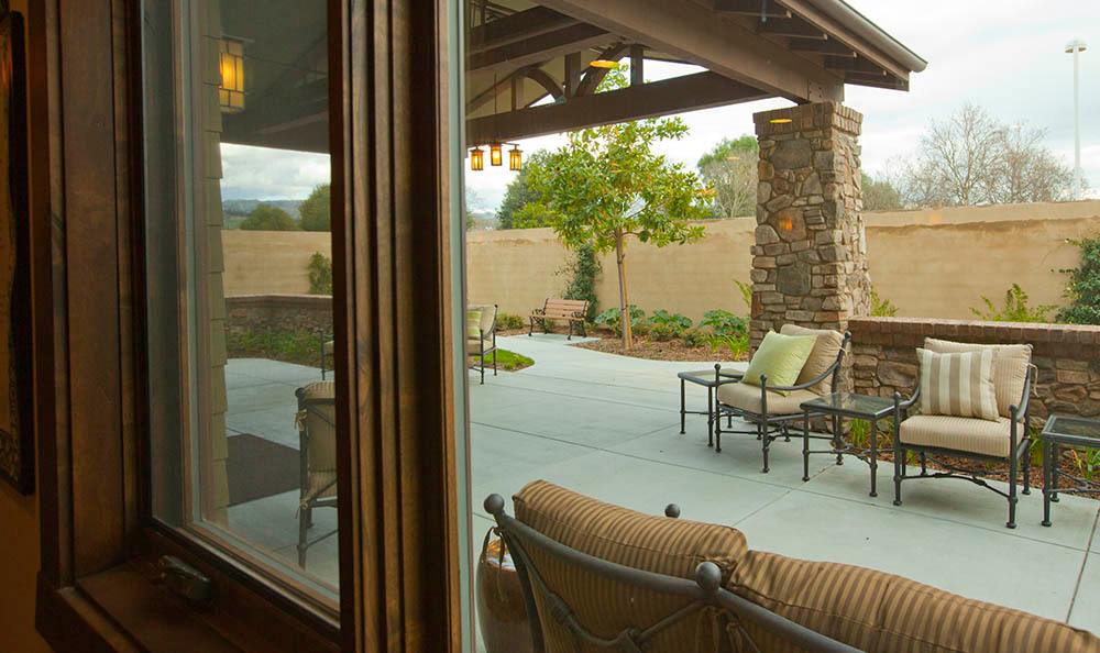 A cozy patio with outdoor seating and a view of a landscaped backyard.