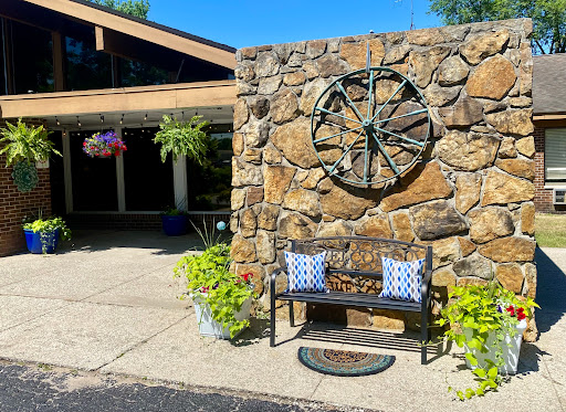 A charming outdoor seating area featuring a stone wall with a decorative clock and blooming flowers.