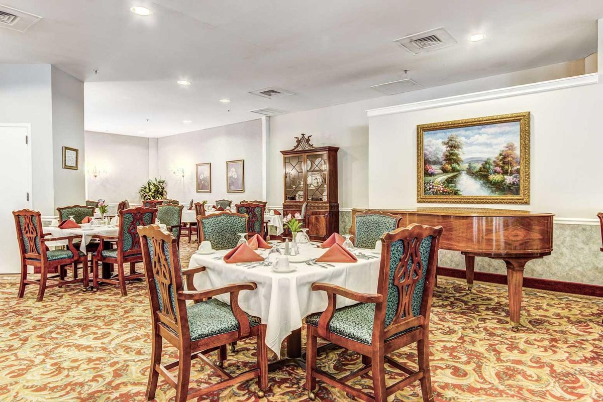 An elegant dining room with neatly arranged tables and chairs, adorned with paintings on the walls.