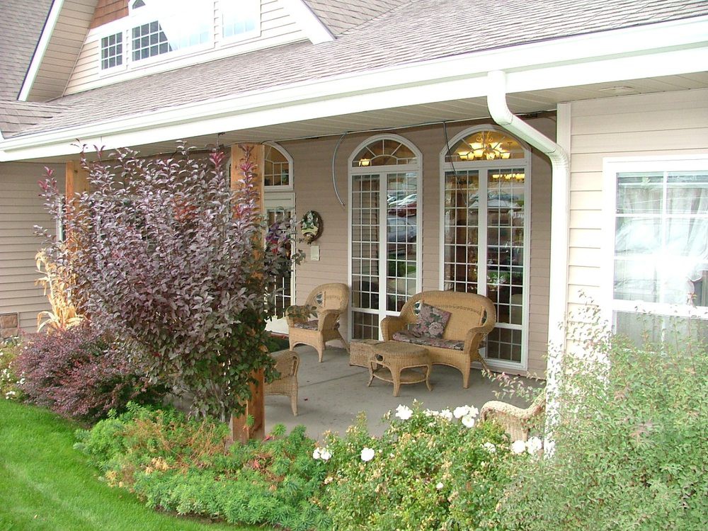 A cozy porch with wicker chairs overlooks a well-maintained garden.